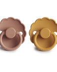 The FRIGG Daisy Natural Rubber Pacifier 2-Pack features two daisy-shaped pacifiers, one in dusty pink and one in mustard yellow, each with a scalloped edge, round handle, natural rubber latex nipple, and FRIGG embossed on the bottom.