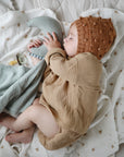 Lifestyle image of a baby swaddled in organic cotton swaddle in Sparrow