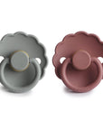 The FRIGG Daisy Natural Rubber Pacifier 2-Pack includes two daisy-shaped pacifiers, one light gray and one muted mauve, both with scalloped edges, round handles, natural rubber latex nipples, and “FRIGG” embossed on the base.