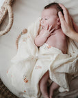 Lifestyle image of a baby swaddled in organic cotton swaddle in Flowers