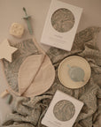 The mushie Organic Cotton Muslin Burp Cloth 2-Pack includes patterned burp cloths in neutral and pastel tones, perfect for baby feeding and play. Pair with boxed bibs, a silicone sippy cup and plate, plus soft star, dice, and pacifier toys.