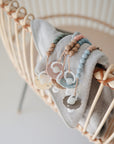 Four pastel mushie Silicone Pacifier Clip | Eva pacifiers with food-grade silicone beads rest on a soft gray blanket over a wicker crib, creating a minimal and cozy setting.