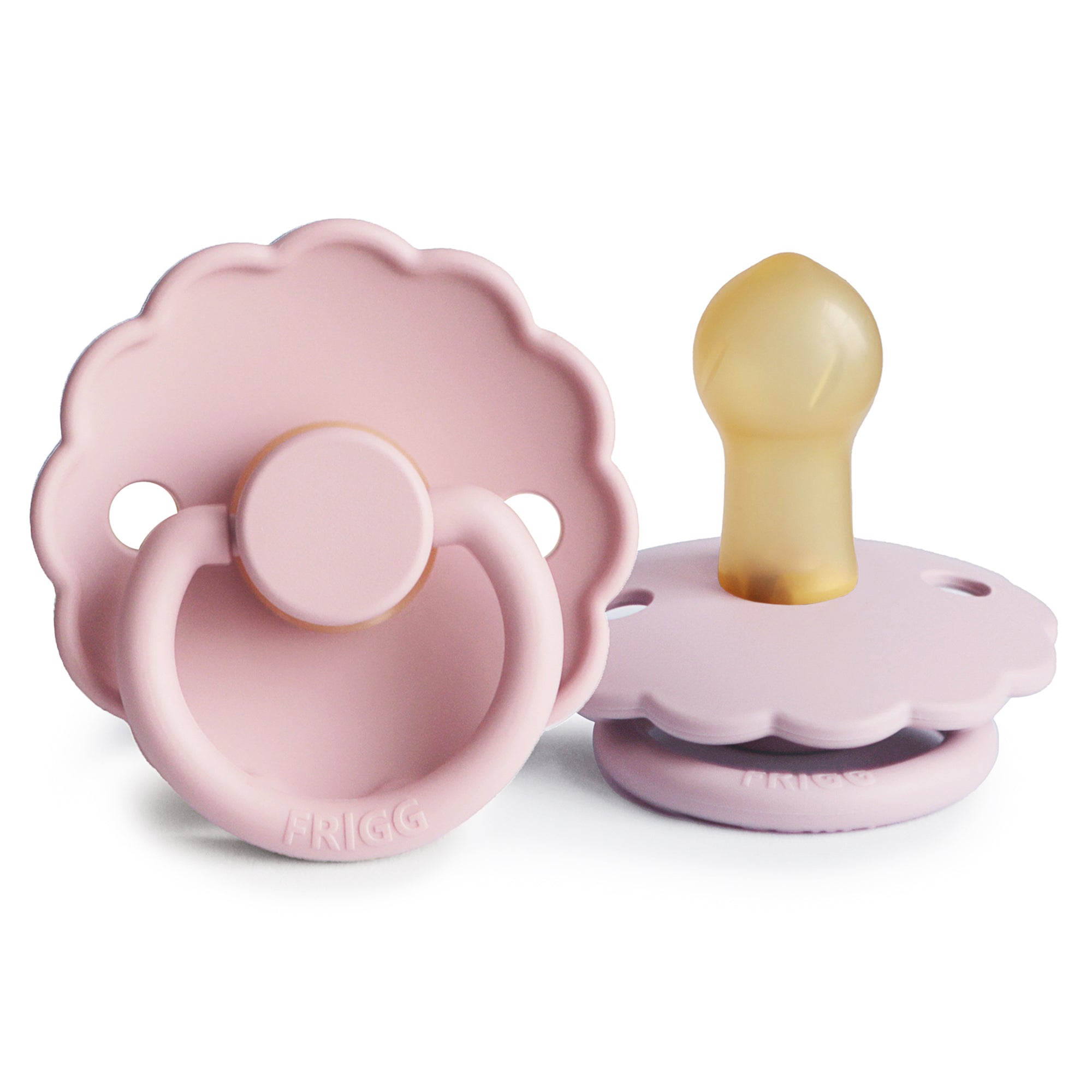 Two Frigg Daisy pacifiers in Baby Pink and Soft Lilac on a white background