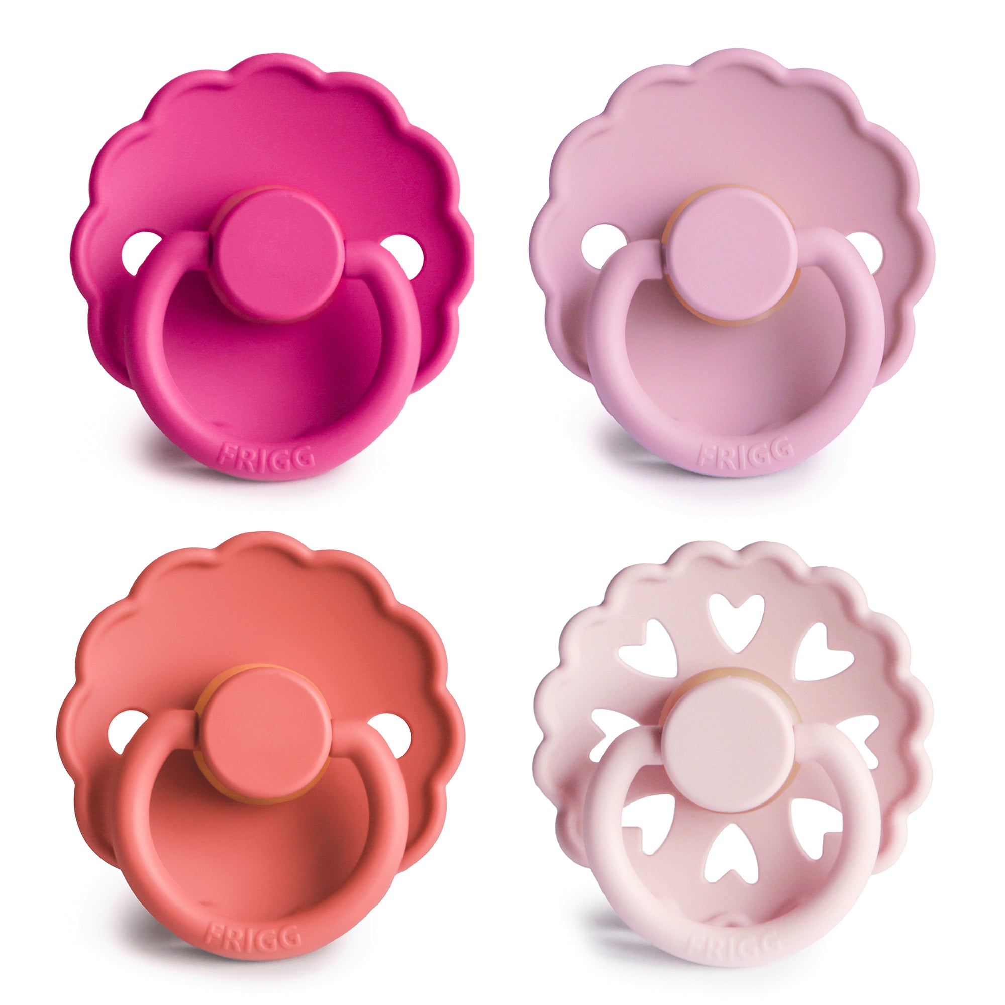 The FRIGG Natural Rubber Pacifier 4-Pack by FRIGG features four classic Danish pacifiers in pink and rose shades, each with a scalloped edge or heart-shaped cutout, arranged in a square on a white background. Made from natural rubber.