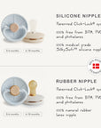 Compare two baby pacifiers: a transparent white silicone nipple and the amber-colored FRIGG Natural Rubber Pacifier 4-Pack by FRIGG, both with a patented click-lock system and labeled for ages 0-6 or 6-18 months.