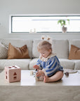 Child playing with shape blocks and a suction spinner ball toy on a coffee table in a living room.