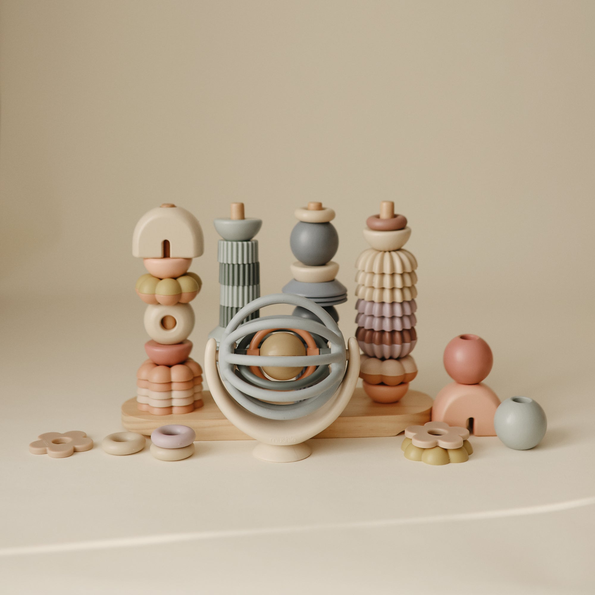 Set of pastel-colored wooden toys and a suction spinner ball toy on a beige background