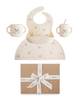 The mushie Bluey Gift Set includes a bib, two-handled cups, and a placemat with pastel animal and star patterns. The silicone baby mealtime set comes in a brown gift box tied with a white ribbon.