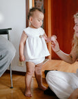 A woman shows a toy to a toddler near mushie Linen Pacifier Clip 2-Pack indoors.