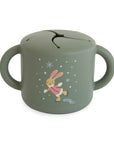 Mushie Snack Cup: green, silicone, two handles, bunny in pink sweater, spill-proof.