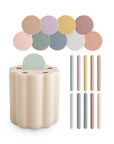 The mushie Coin & Tube Sorting Set features a beige scalloped sorter with a mint green lid, ten pastel lids, and matching straws in pink, yellow, green, blue, purple, and white—perfect for developing fine motor skills.