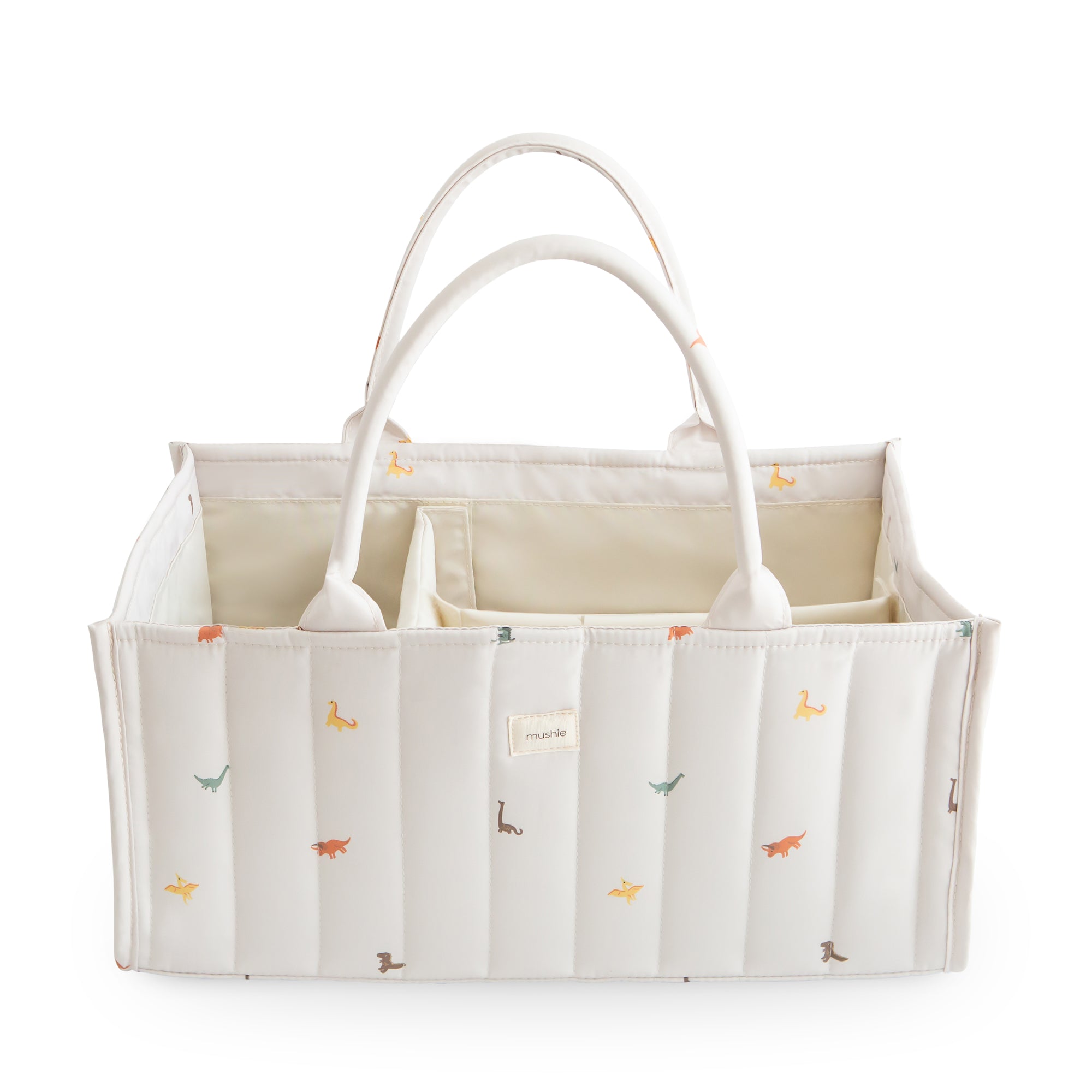 Mushie Diaper Caddy: white quilted organizer with handles, colorful dinosaur print.