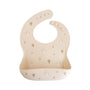 Mushie Silicone Baby Bib—beige with colorful cup and challah design, adjustable neck strap.
