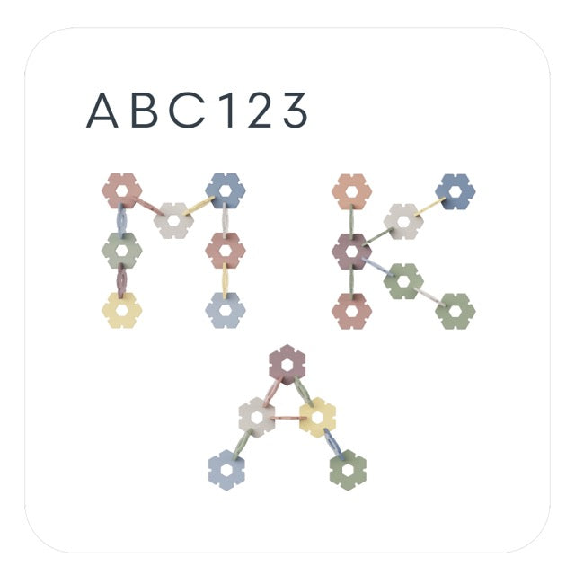 Flower-shaped plastic building pieces in pastel colors are connected together to form the shapes of a dog and a person, with ABC123 written above in black letters on a white background.