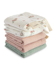 A set of five mushie Muslin Cotton Washcloths in soft pastels—white with floral print, light pink, and sage green—neatly folded on a white background.