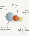 The mushie Nesting Spheres Sensory Toy features three uniquely textured silicone balls that nest together, provide gentle rattle sounds, and are made from food-grade silicone free of BPA, BPS, PVC, and phthalates for safe baby development.