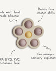 The mushie Flower Press Toy features six popper bubbles and is made from food-grade silicone, free of BPA, BPS, PVC, and phthalates. It supports fine motor skill development and sensory play, with petal text highlighting its benefits.