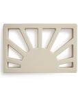 The mushie Sun Teether is a beige, rectangular silicone teether with a sun-inspired cutout design featuring a semicircle and upward rays.