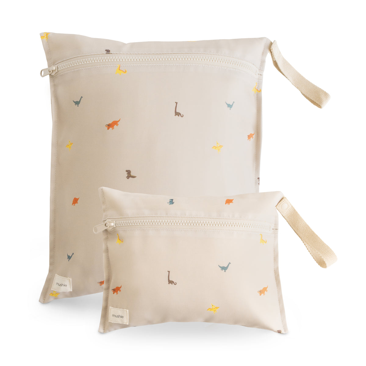 Two beige mushie Water Resistant Wet bags with a colorful dinosaur pattern and side carry straps.