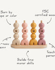 The Mushie Wooden Multi Shape Stacker features four rods with assorted shapes and colors. FSC certified wood, non-toxic paint, and handwritten labels emphasize sorting by shape or color and building fine motor skills.