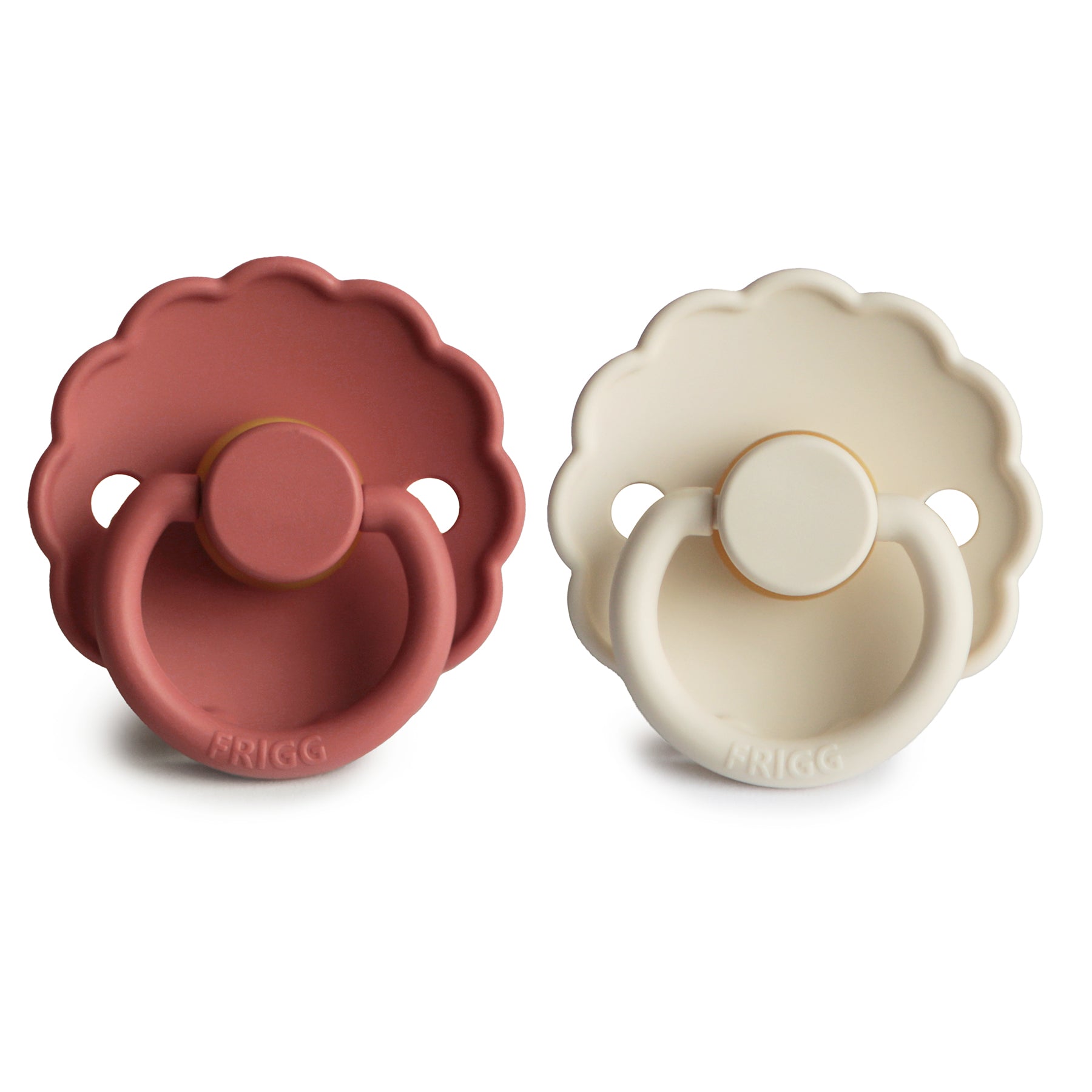 The FRIGG Daisy Natural Rubber Pacifier 2-Pack includes two pacifiers in muted red and cream, both with scalloped daisy edges, round handles, identical designs, and natural rubber latex nipples for baby's comfort.