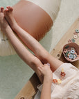 Child by a pool playing with mushie Square Dinnerware Bowls and colorful flower pieces.