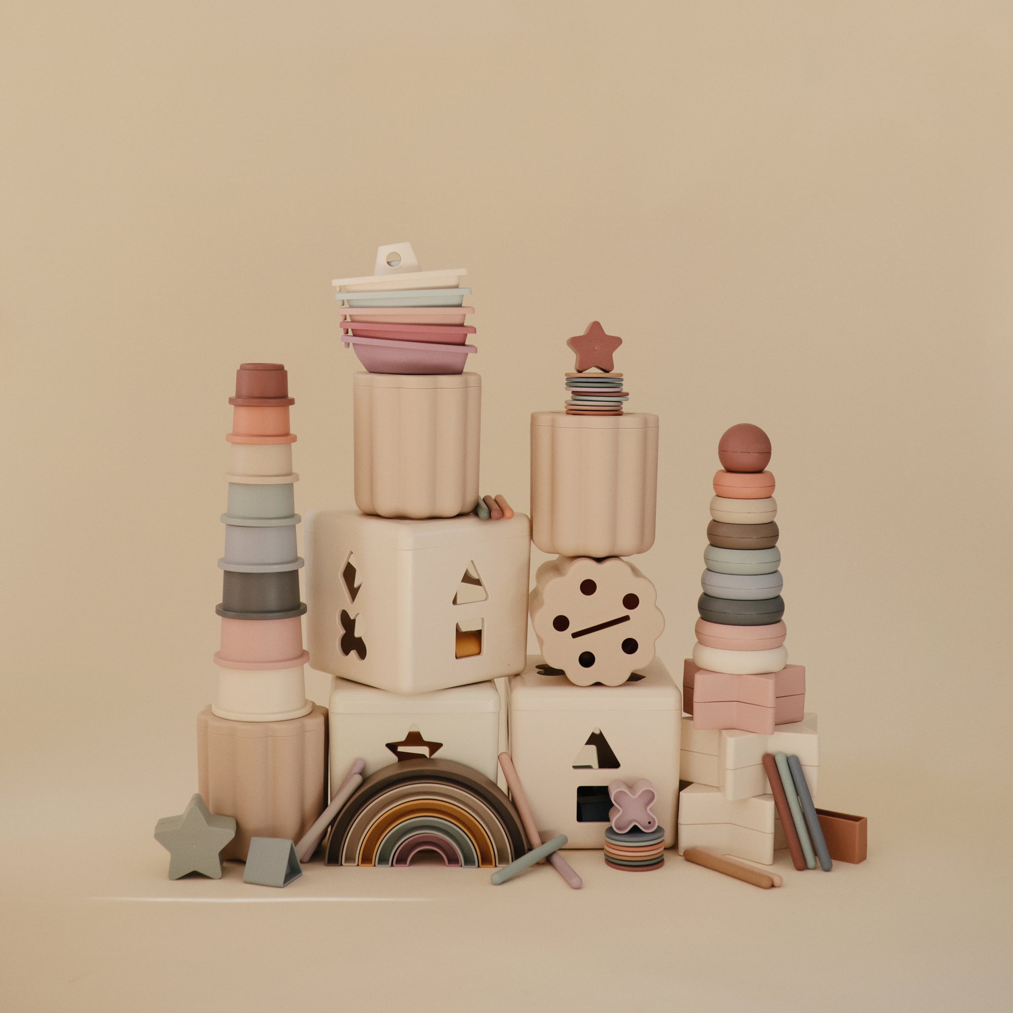 The mushie Coin &amp; Tube Sorting Set is displayed against a beige background, offering a visually appealing educational toy that encourages fine motor skill development.