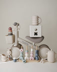 Mushie Mini Toddler Bike with pastel stacking toys, cups, and teapots displayed around it.