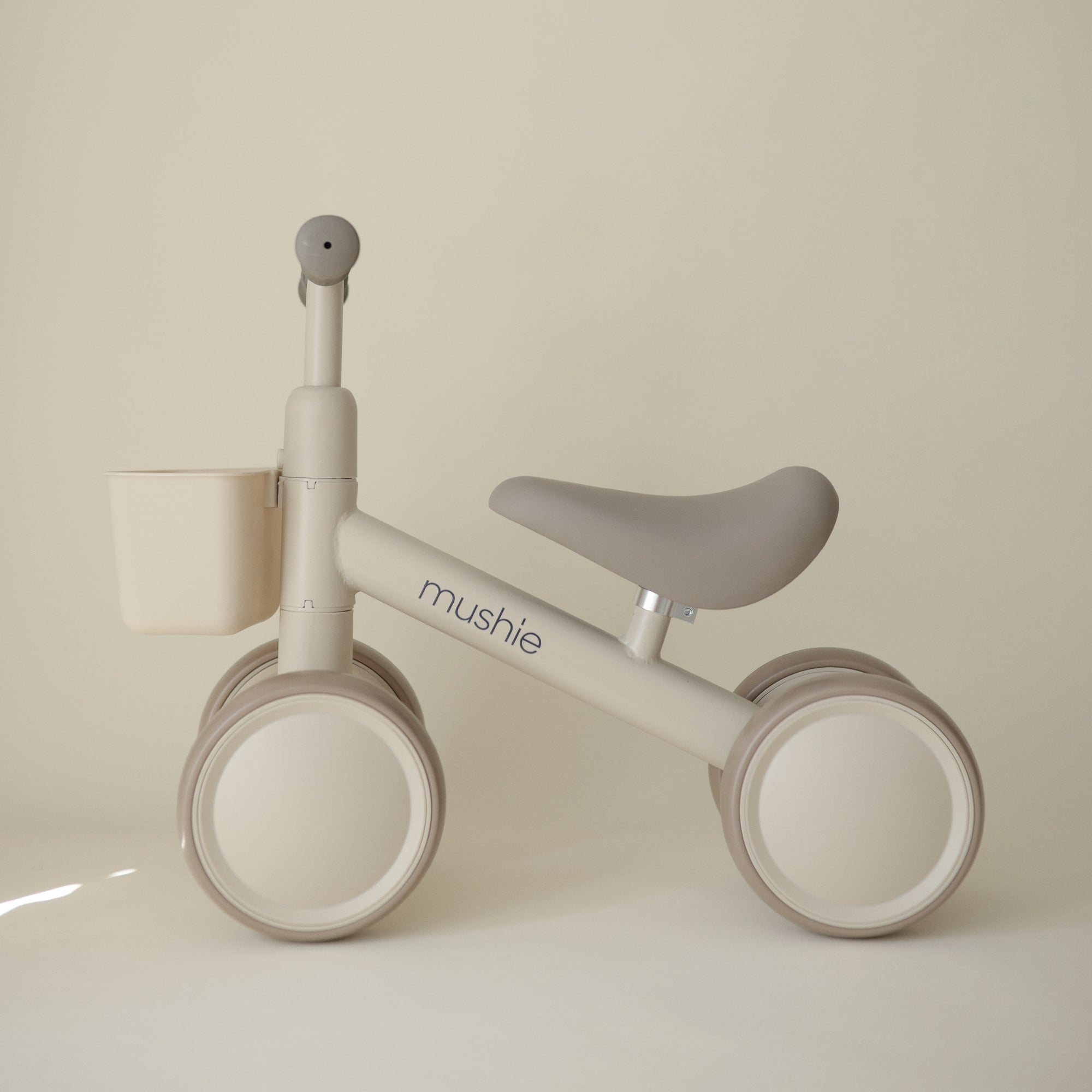 Mushie Mini Toddler Bike in beige &amp; cream with basket—ideal first bike for toddlers.
