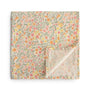 The mushie Organic Cotton Muslin Swaddle Blanket in Pastel Blooms, featuring a soft floral pattern, is shown folded with one corner turned up to reveal the reverse side.