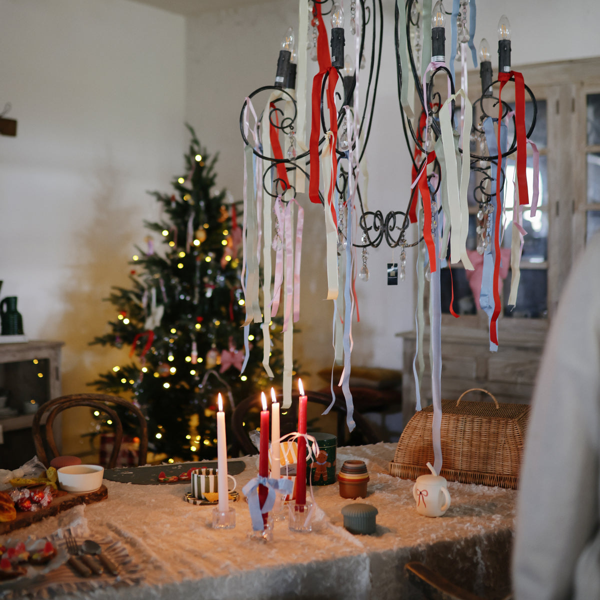 Festive table with candles, ribbons, and mushie Silicone Baby Food Containers for daycare snacks.