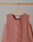 Lifestyle image of a Mushie Sleep Bag in Cedar on a hanger.